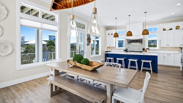 A modern kitchen with white cabinets, a blue island, and pendant lighting. - The Boat House at Kiva Dunes (Gulf Shores)