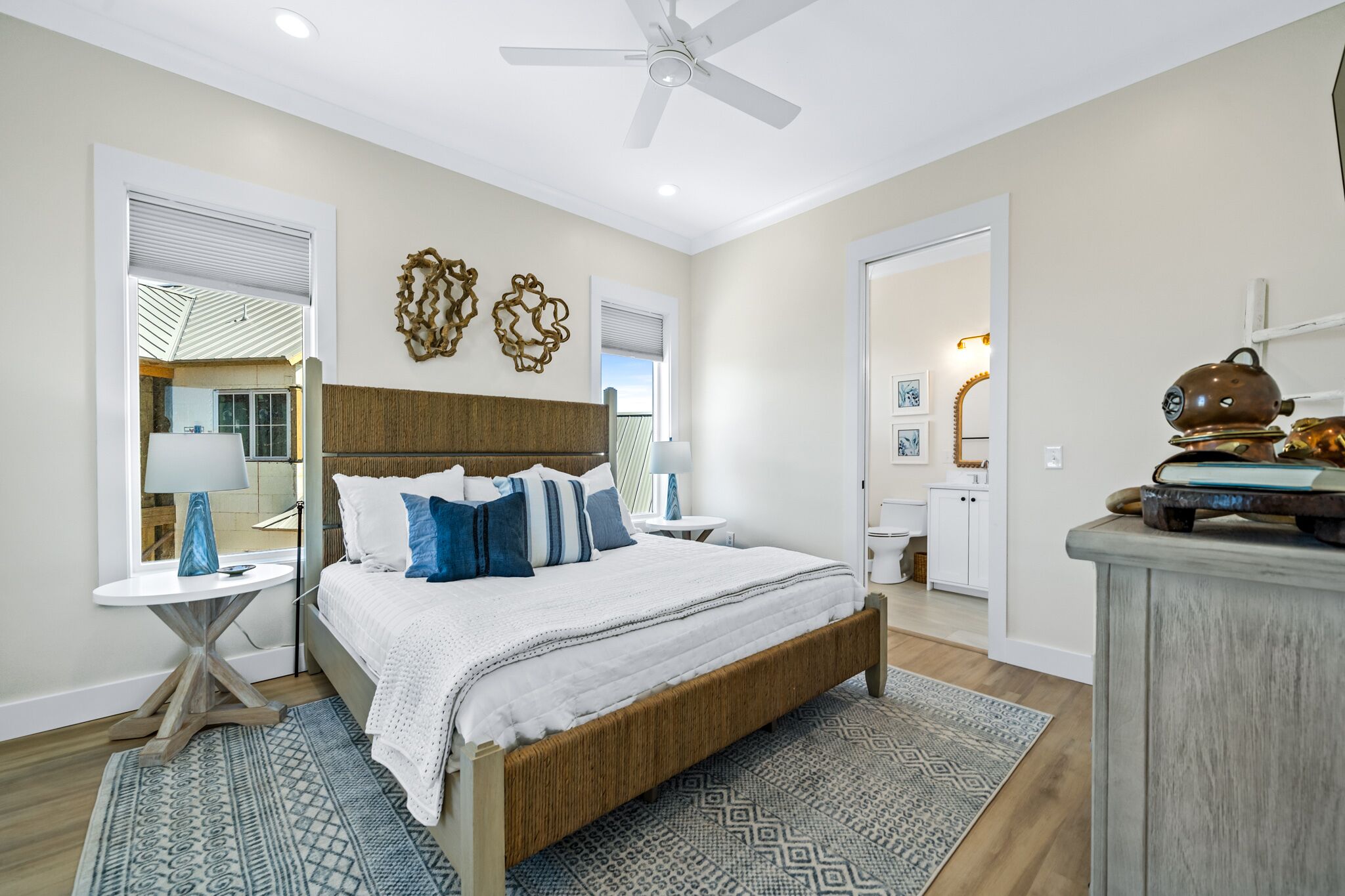 A bedroom with a bed, bedside tables, a ceiling fan, and a view of the bathroom.