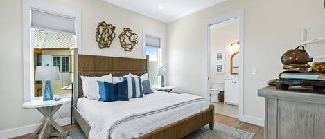 A bedroom with a bed, bedside tables, a ceiling fan, and a view of the bathroom.