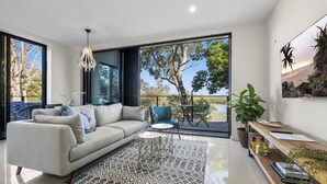A modern living room with a sofa, a coffee table, and a view of the outdoors. - Paradise on Gregory G04/21 Gregory St SWR (South West Rocks)