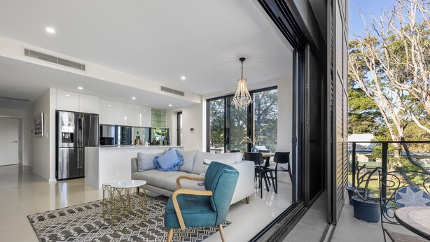 A modern kitchen with stainless steel appliances, a dining area with a white table and chairs, and a balcony with outdoor seating. - Paradise on Gregory G04/21 Gregory St SWR (South West Rocks)