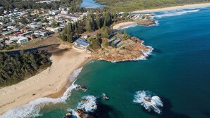 An aerial view of a coastal area with a beach, ocean, and residential buildings. - Paradise on Gregory G04/21 Gregory St SWR (South West Rocks)