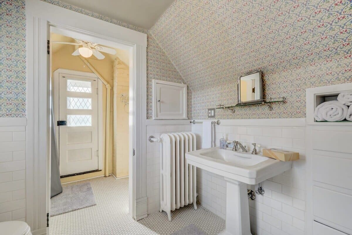 A bathroom with a white sink, a radiator, and a shower area.