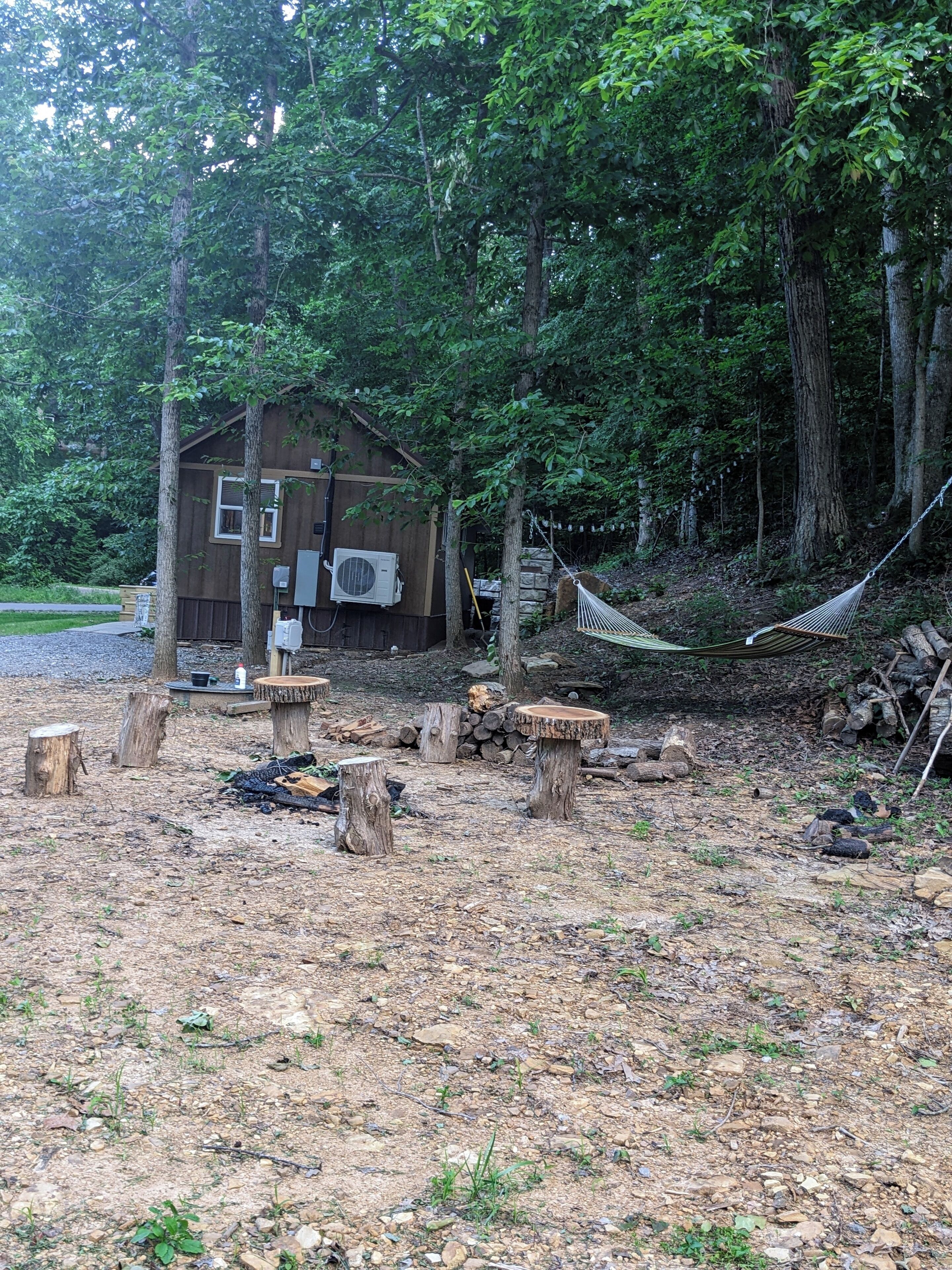 Une cabane rustique avec une façade en bois, un petit porche et un hamac.