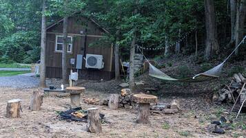 Une cabane rustique avec une façade en bois, un petit porche et un hamac.