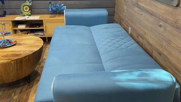 A modern living room with a blue sofa, wooden coffee table, and a TV displaying a beach scene.