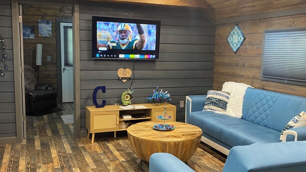 Una sala de estar moderna con un sofá azul, una mesa de centro de madera y un televisor montado en la pared.