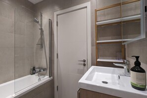 Un baño con ducha, lavamanos y espejo.