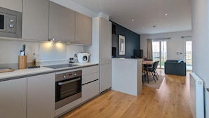 Een moderne keuken met inbouwapparatuur, een eethoek met tafel en stoelen, en uitzicht op de omgeving.