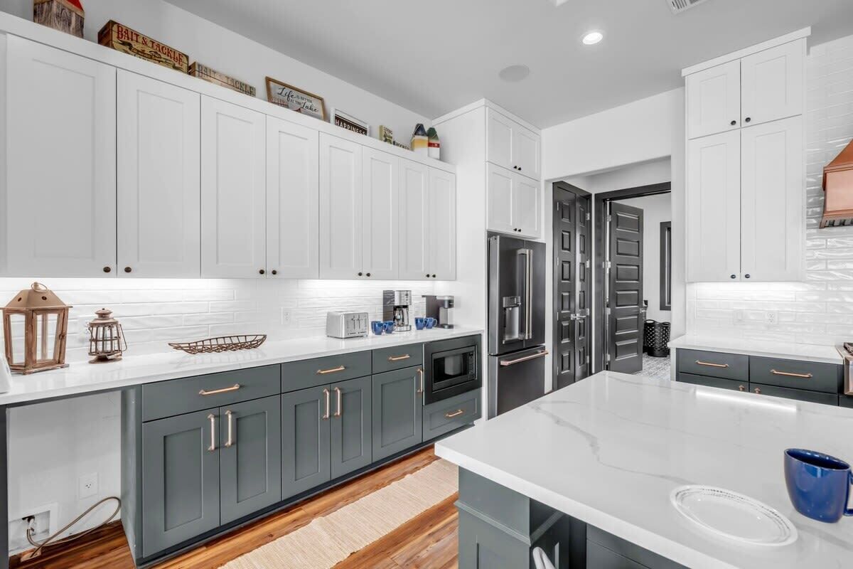 A modern kitchen with white cabinets, a marble countertop, and stainless steel appliances.