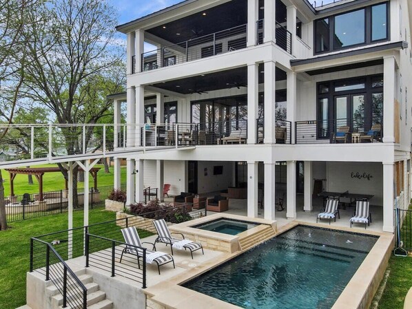 A modern two-story house with a swimming pool, outdoor seating, and a covered patio area.