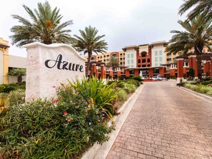 A hotel entrance with a sign reading "Azure," surrounded by lush greenery and palm trees.