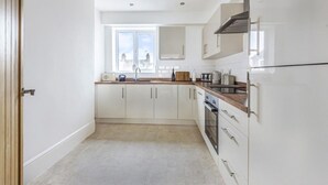 A modern kitchen with white cabinets, a wooden countertop, and a built-in oven. - Sea Breeze-Cliff Terrace -Hunstanton. 3 Bedroom Apartment -Sea View  (Hunstanton)