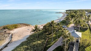 A beach resort with a clear view of the ocean, palm trees, and a pathway leading to the beach.