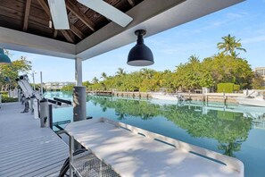 A swimming pool area with lounge chairs and a ceiling fan. - Conch Cottage (Marathon)