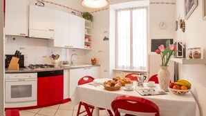 Una cocina con armarios blancos, sillas rojas y una mesa de comedor dispuesta para el desayuno.