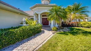 A house with a paved driveway, a red door, and a statue in front.