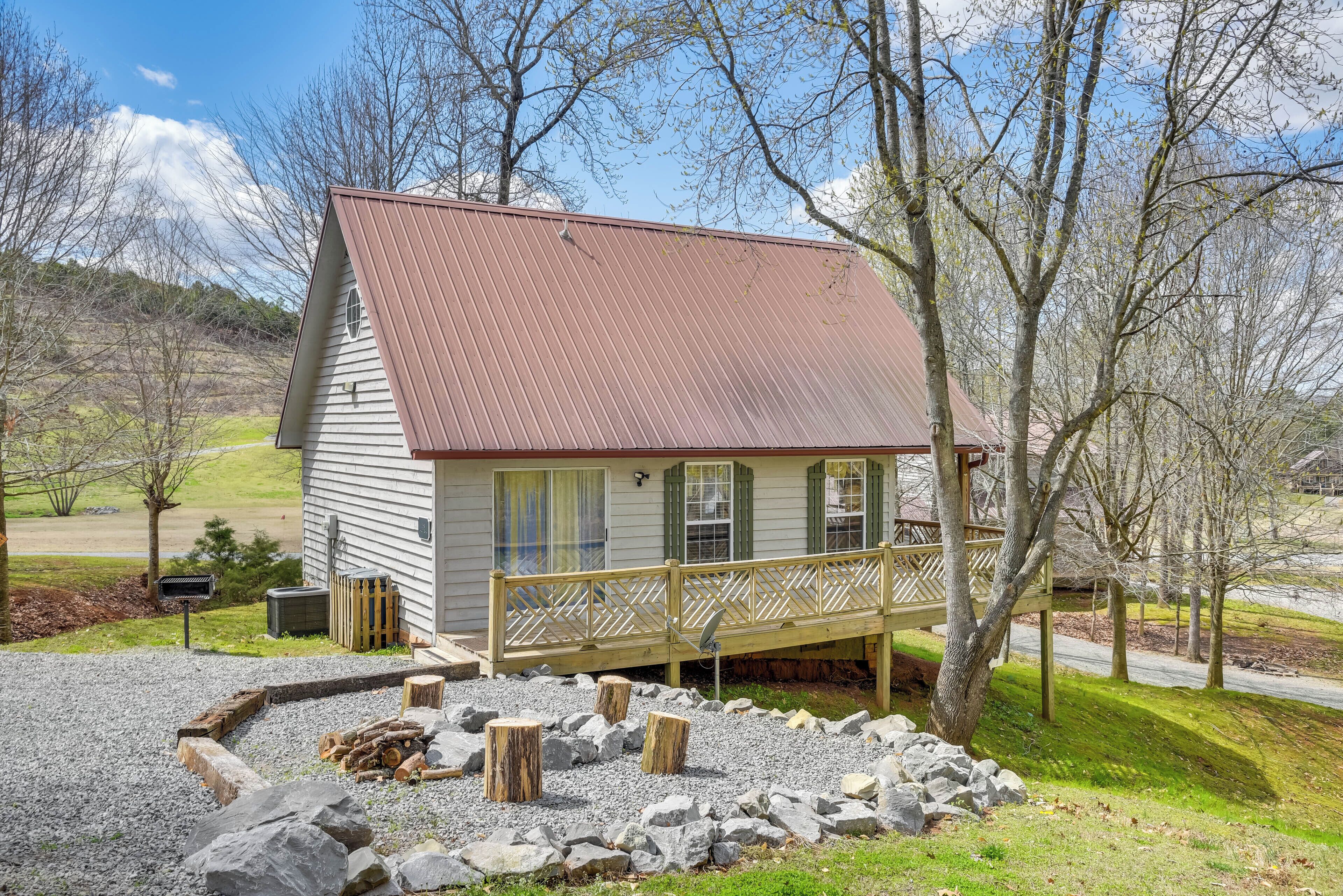 A small cabin with a wooden deck and a stone fire pit.