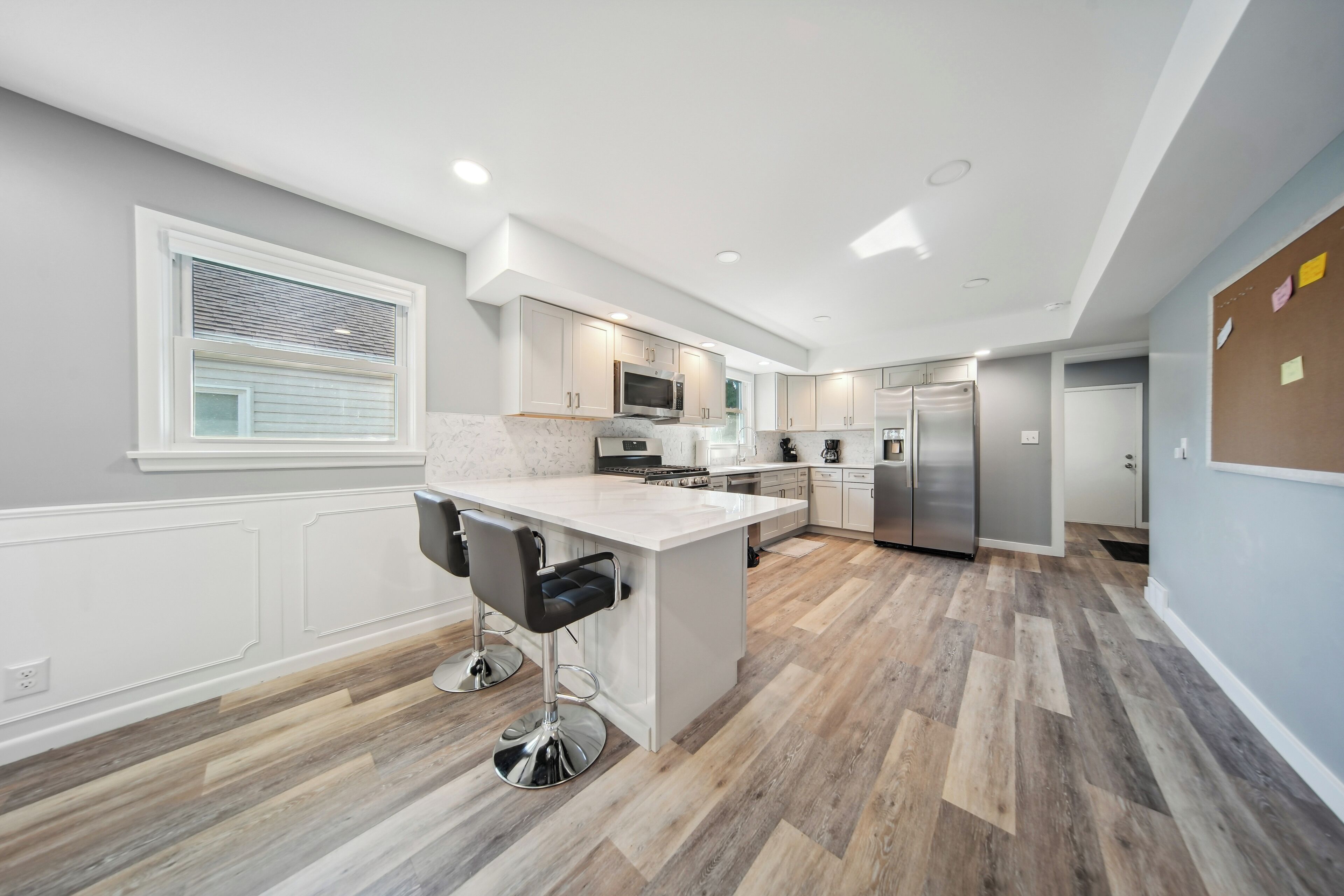 A modern kitchen with a central island, bar stools, and a refrigerator.