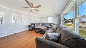 Ein geräumiges Wohnzimmer mit einer großen Eckcouch, einem Couchtisch und einem Deckenventilator.
