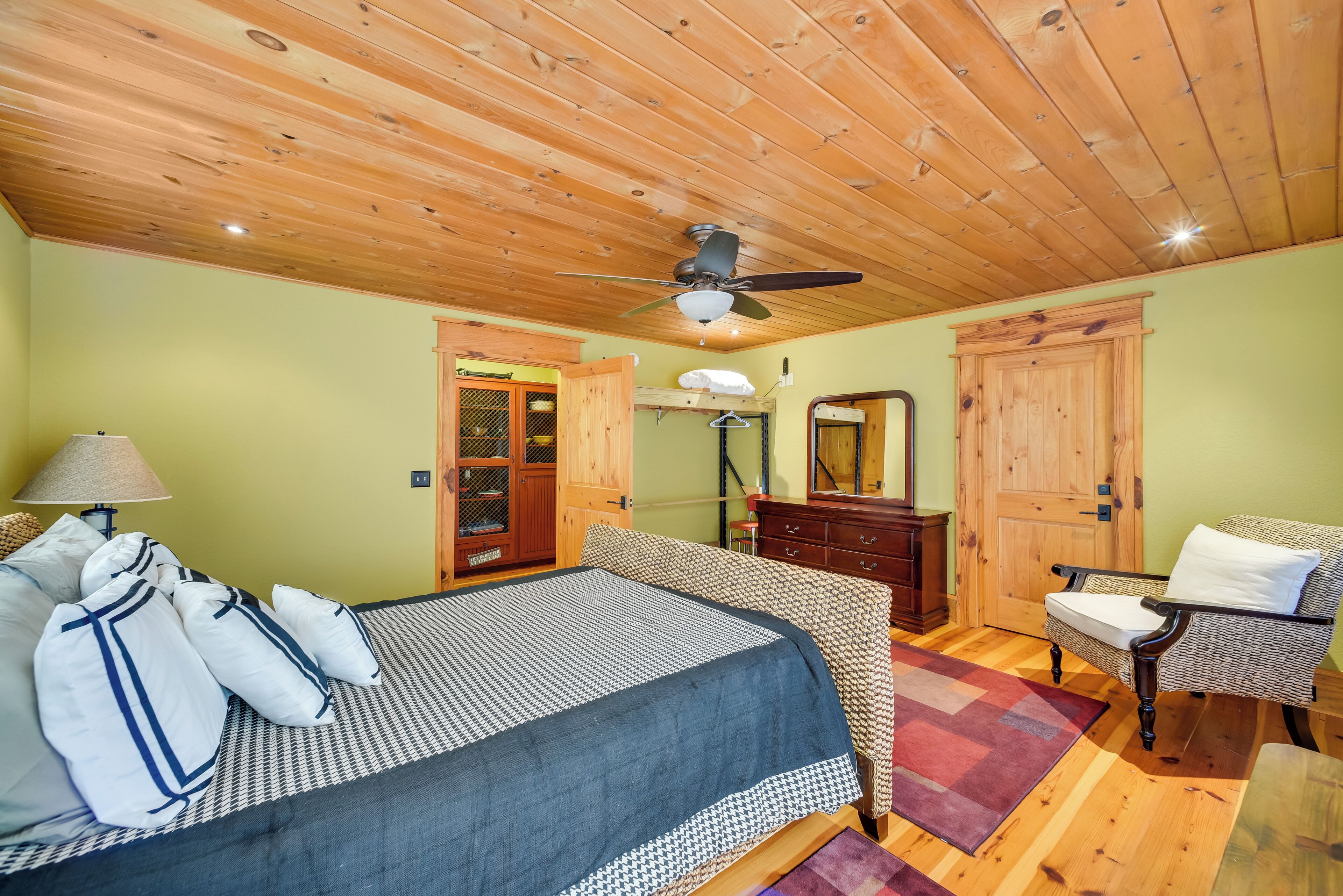 A bedroom with a bed, a chair, a dresser, and a ceiling fan.