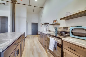 Uma cozinha moderna com bancada de mármore, eletrodomésticos de aço inoxidável, armários de madeira e forno embutido.