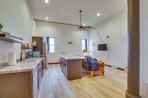 Uma cozinha espaçosa com ilha central, armários de madeira e ventilador de teto.