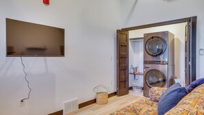 Un dormitorio con cama, televisor montado en la pared, lavadora y secadora.