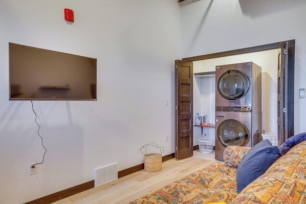 A bedroom with a bed, a television mounted on the wall, a washing machine, and a dryer. - Loft-style Downtown Cashton Studio: Dogs Welcome! (Cashton)