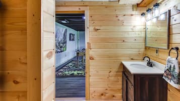 A wooden interior with a wooden wall, a sink, a mirror, and a door leading to another room.