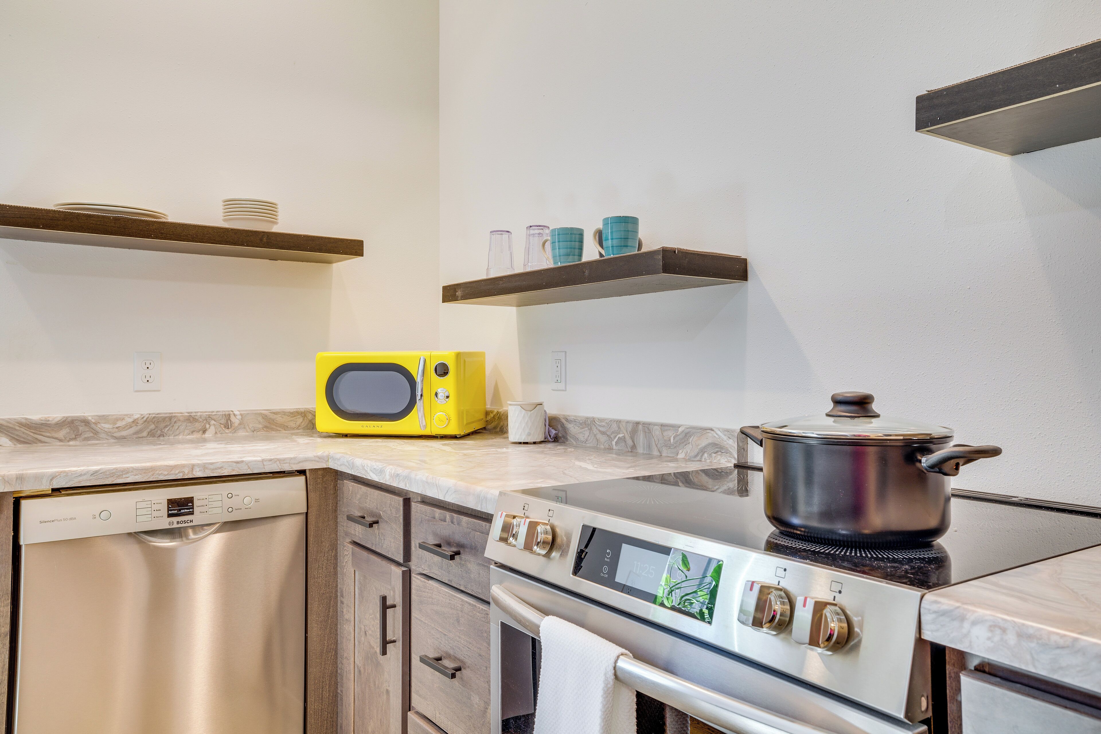 A kitchen with a Bosch dishwasher, a microwave, a stove, and a pot on the stove.