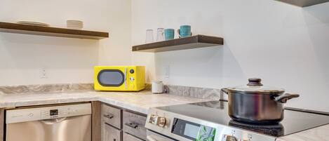 A kitchen with a Bosch dishwasher, a microwave, a stove, and a pot on the stove.