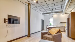A modern living room with a sofa, a coffee table, and a flat-screen TV mounted on the wall. - Step-free Cashton Apartment: Steps to Downtown! (Cashton)