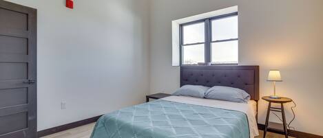 A bedroom with a bed, a window, a nightstand, and a lamp.