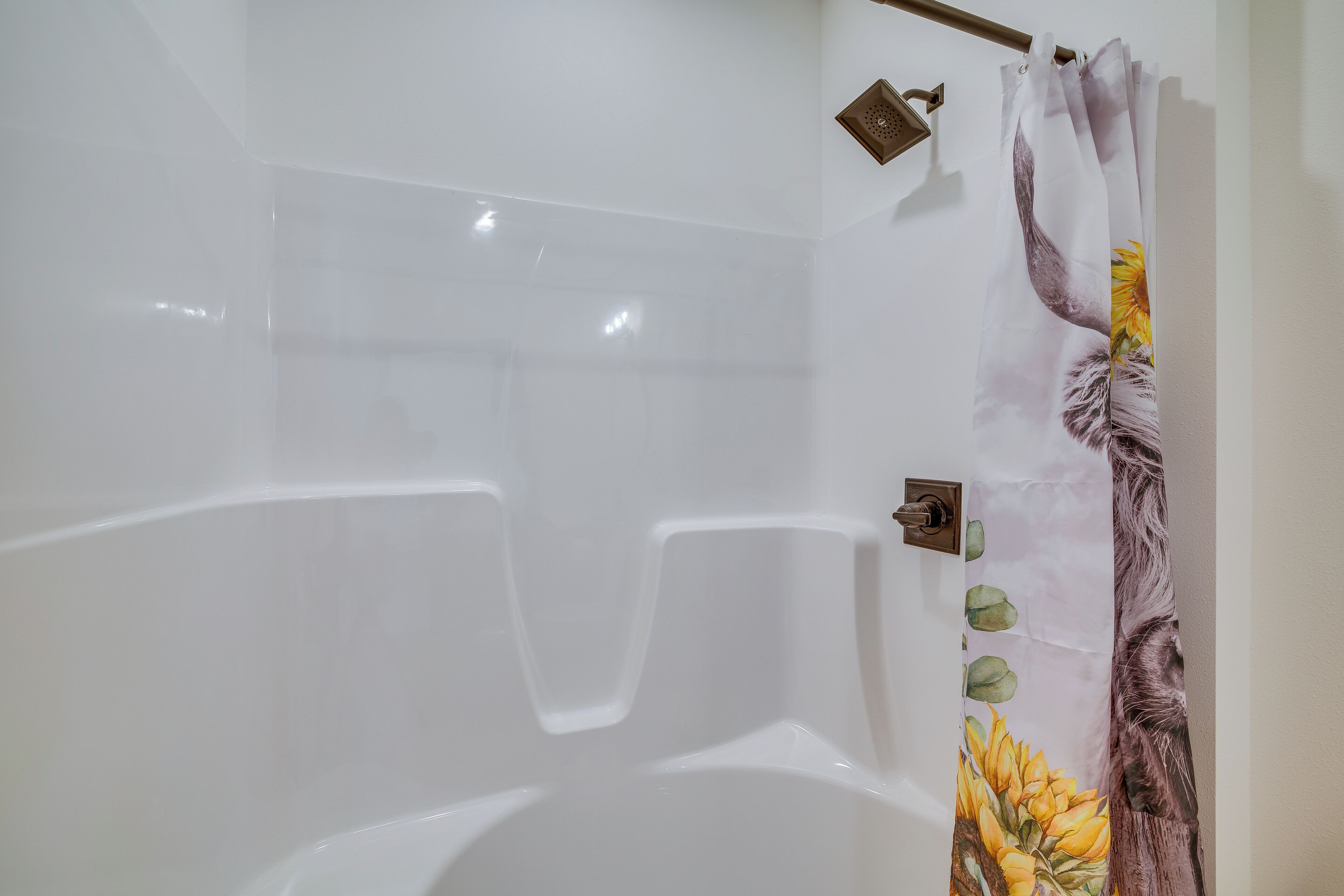 Un baño con una bañera blanca, una cortina de ducha con diseño floral y un perchero para toallas.