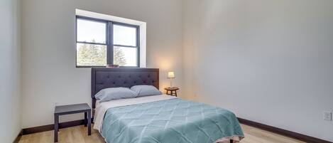 A bedroom with a bed, a nightstand, a window, and a ceiling fan.