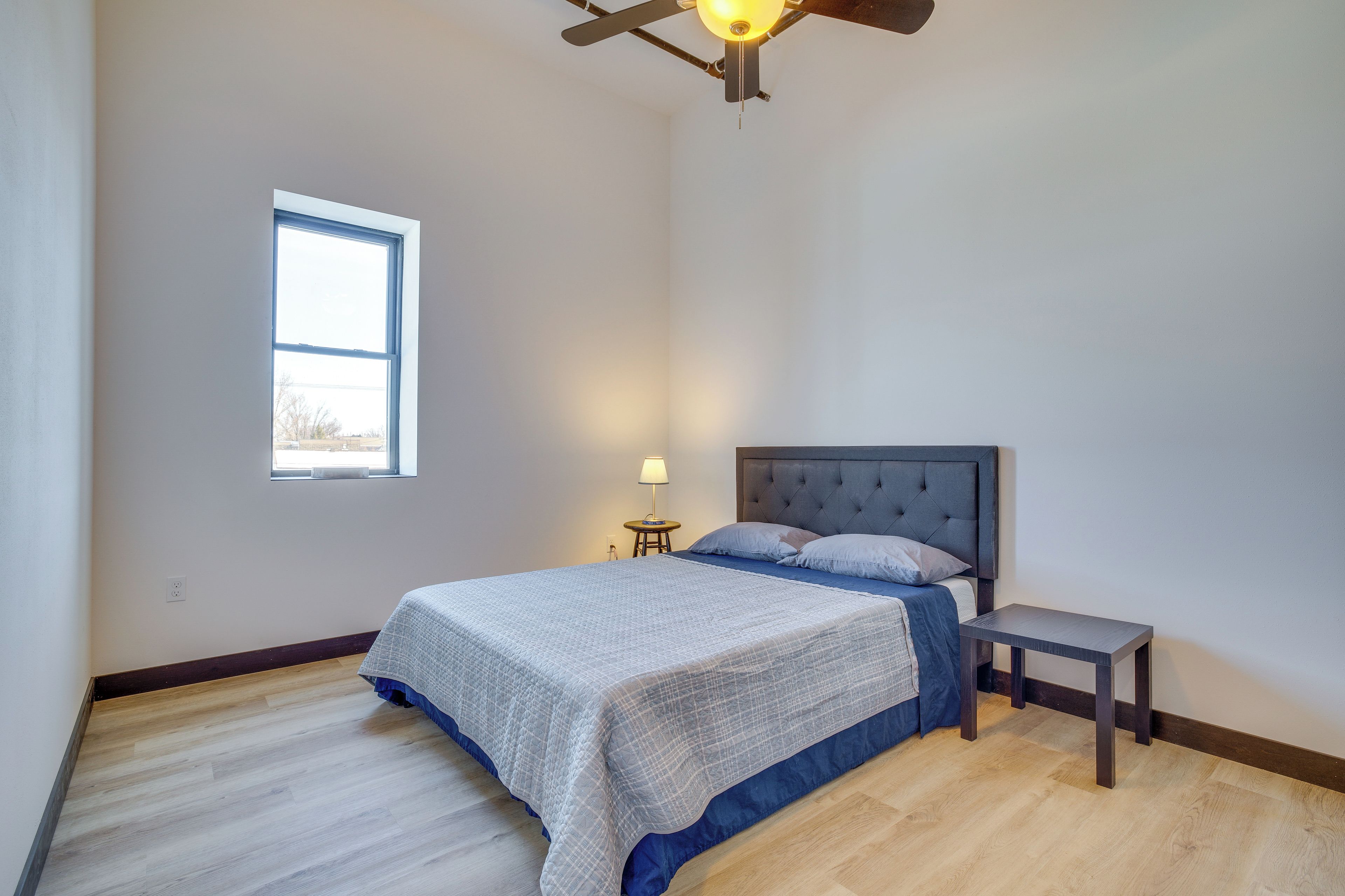 A bedroom with a bed, a nightstand, a lamp, and a window.