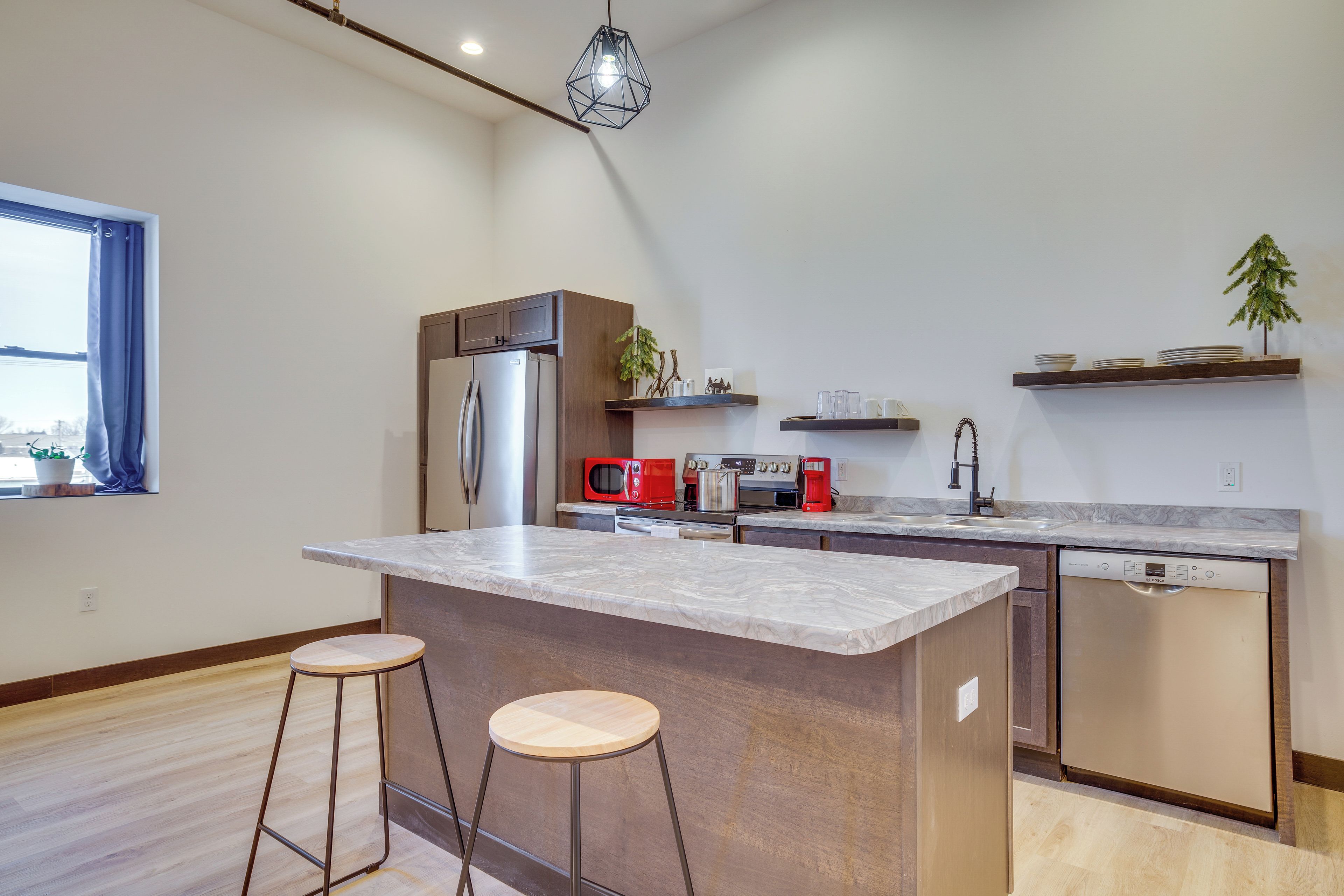 A modern kitchen with a central island, stainless steel appliances, and wooden bar stools.