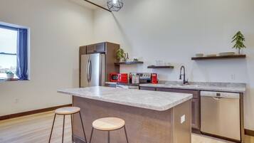 A modern kitchen with a central island, stainless steel appliances, and wooden bar stools.