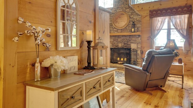 A cozy cabin interior with wooden walls, a stone fireplace, a comfortable chair, and a rustic decor. - Picturesque Clayton Cabin w/ Mountain Views! (Clayton)