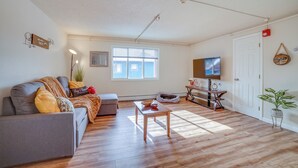 A living room with a grey sofa, wooden coffee table, and a TV on the wall. - Anchorage Apartment Rental w/ Mountain Views! (Anchorage)