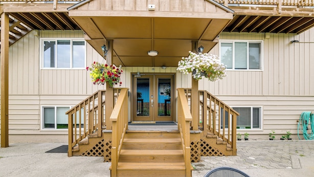 A wooden staircase leading to a building entrance with a covered porch, potted plants, and a visible door. - Anchorage Apartment Rental w/ Mountain Views! (Anchorage)