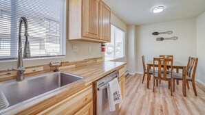 A kitchen with wooden cabinets, a stainless steel sink, and a dining area with wooden chairs and a table. - Anchorage Apartment Rental w/ Mountain Views! (Anchorage)
