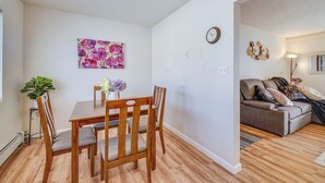 A dining area with a wooden table and chairs, a potted plant, and a wall clock. - Quiet Anchorage Retreat, 4 Mi to Earthquake Park (Anchorage)
