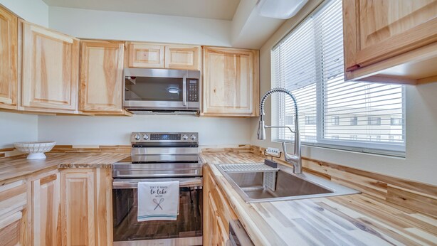A modern kitchen with wooden cabinets, stainless steel appliances, and a window with blinds. - Quiet Anchorage Retreat, 4 Mi to Earthquake Park (Anchorage)
