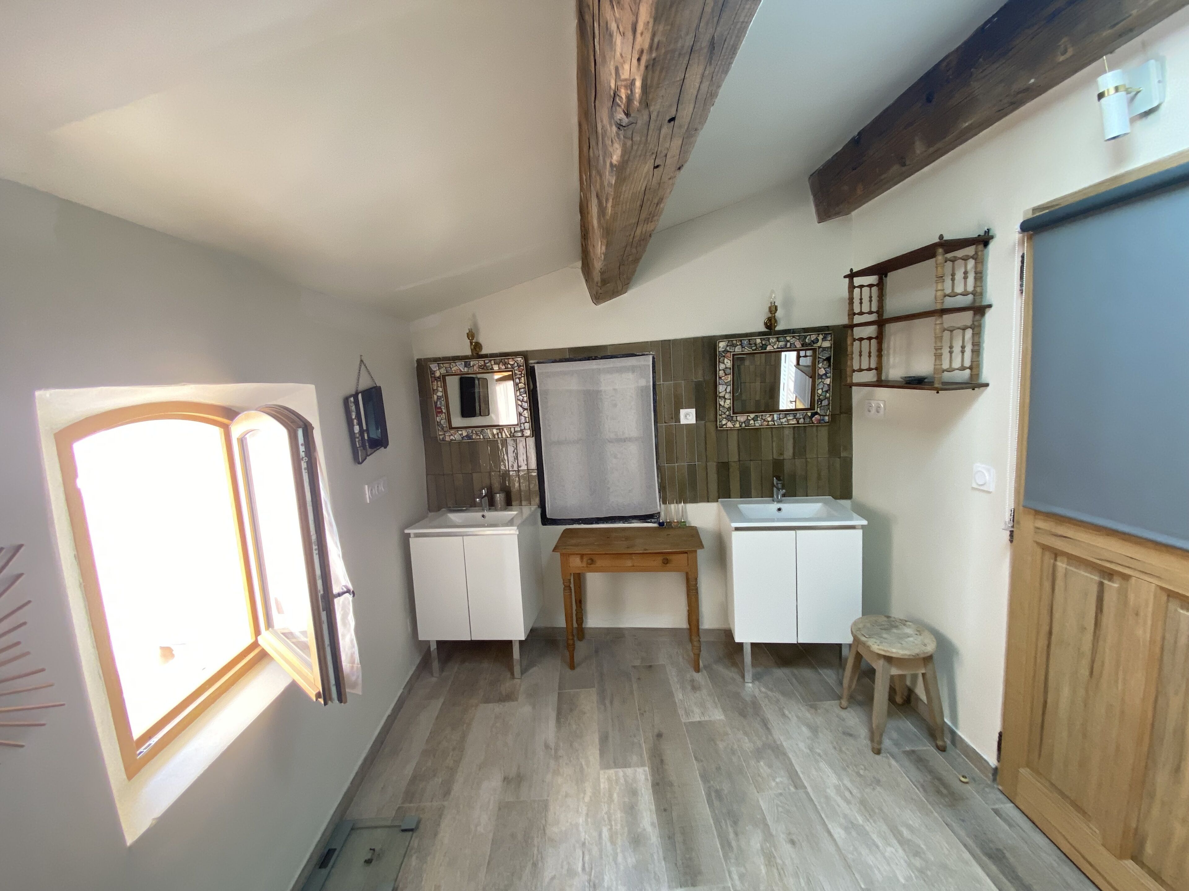 Ein Badezimmer mit Holzboden, einem Fenster, zwei Waschbecken und einem Spiegel.