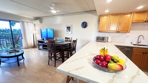 A modern kitchen with wooden cabinets, a built-in oven, and a large island with a fruit bowl. - Bright Kihei Renovated Condo New AC Steps to Kamaole II Beach and Pool (Kihei)