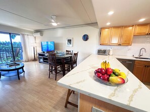 A modern kitchen with wooden cabinets, a built-in oven, and a large island with a fruit bowl.