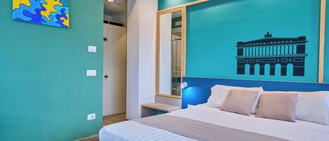 A bedroom with a bed, a wall painting, and a large mirror.