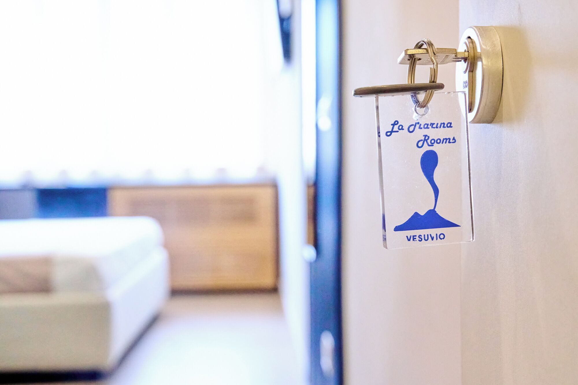Eine Hotelzimmertür mit einem Schild, das 'La Garona Rooms' und 'Vesuvius' anzeigt.